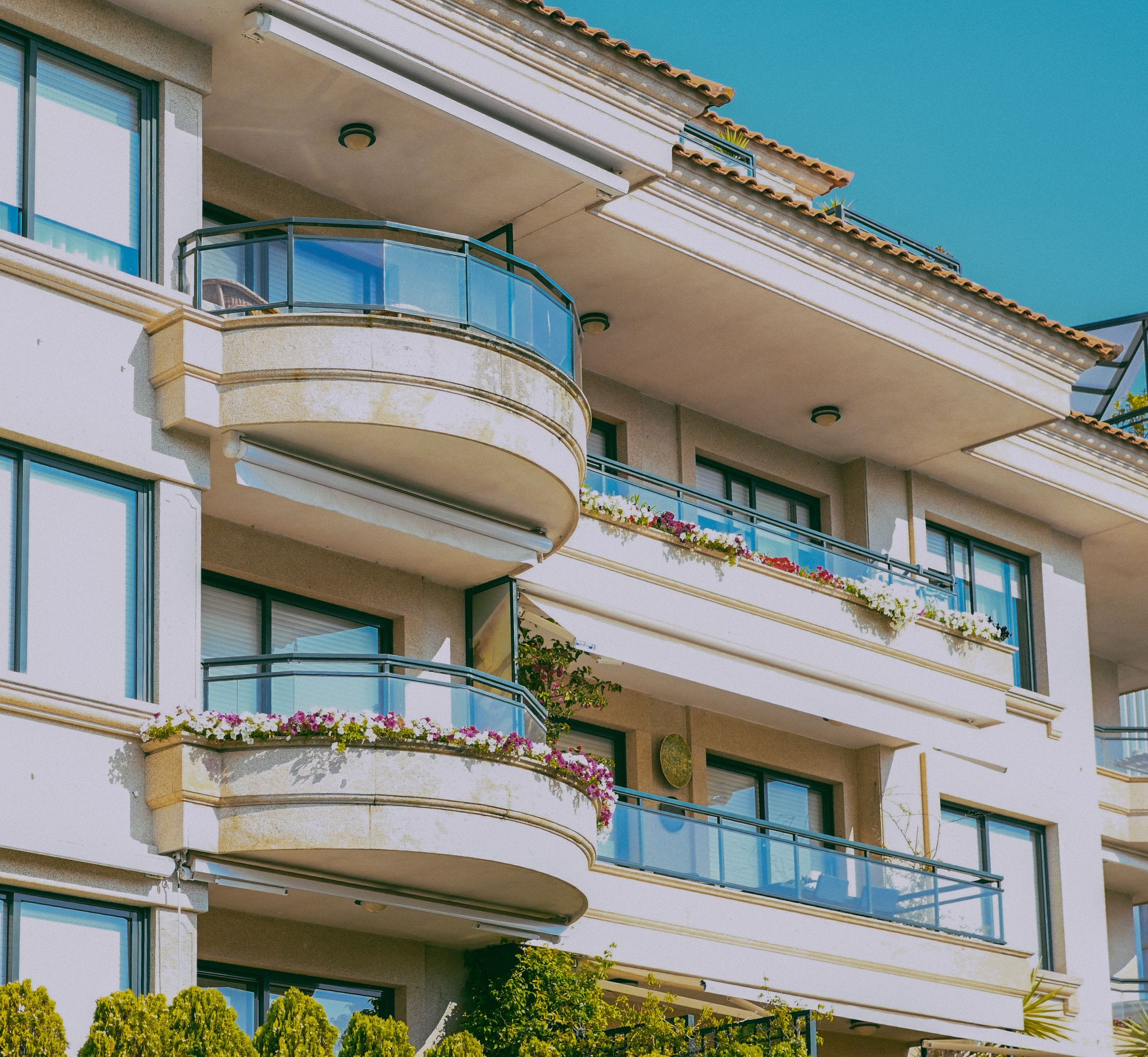 Stylish architecture featuring glass balconies and flower decorations on a sunny day.